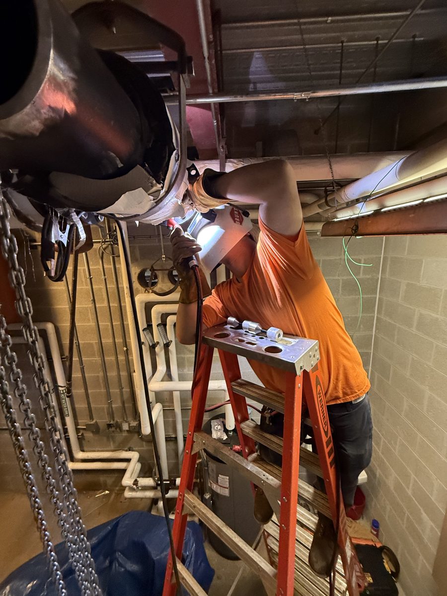 Hay's Welding welder working overhead on industrial pipe from a ladder